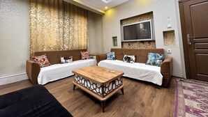 A living room with two sofas, a coffee table, a TV mounted on the wall, and a patterned rug. - The New Season Apart (Istanbul)