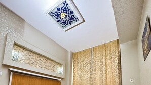 A bedroom with a bed, a nightstand, a window with curtains, a wall-mounted light fixture, and a ceiling light. - The New Season Apart (Istanbul)