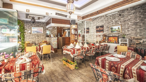 A restaurant with multiple tables set for dining, featuring traditional decor and a stone wall backdrop. - The New Season Apart (Istanbul)