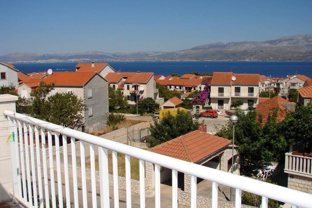 A coastal residential area with houses, a clear blue sky, and a view of the sea.