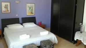 A bedroom with a bed, two pillows, a bedside table with a lamp, a small table with a vase, and a wardrobe. - Apartments Magda (Supetar)