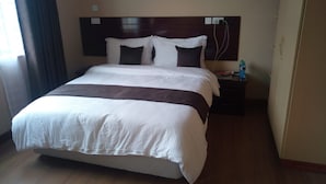 A large bed with white and brown bedding, a wooden headboard, and a nightstand with a water bottle. - Scenic View Apartments Kilimani (Nairobi)