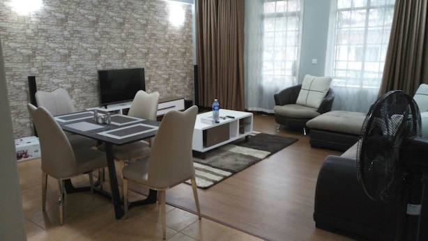 A modern living room with a stone wall, a flat-screen TV, a dining table with chairs, a sofa, and a fan. - Scenic View Apartments Kilimani (Nairobi)