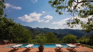 A pool with lounge chairs and a view of a mountainous landscape. - Villa Barsotti (Pescaglia)