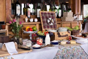 Un ricco buffet per la colazione con diverse pietanze, una selezione di vini e un cesto di vimini.