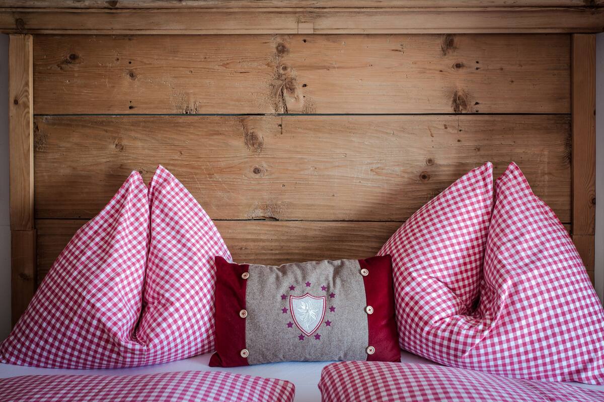 A wooden headboard with a checkered pillow and a pillow with a shield emblem.