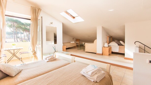 Une pièce spacieuse avec deux lits, un balcon, une lucarne et un petit coin salon.