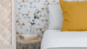 A bedroom with a bed, a bedside table with a vase, and a geometric-patterned wall. - Go Madrid Apartments by Olala Homes (Madrid)