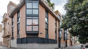 A modern building with a large central window, a brick facade, and a metal fence at the base. - Go Madrid Apartments by Olala Homes (Madrid)