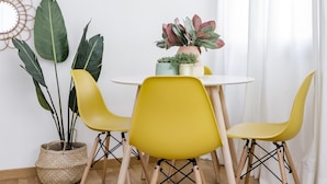 A dining area with a round table, yellow chairs, and a hanging light fixture. - Go Madrid Apartments by Olala Homes (Madrid)