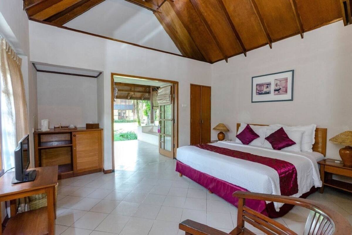 Une chambre d’hôtel avec un lit, une table de chevet, une lampe et une vue sur l’extérieur.