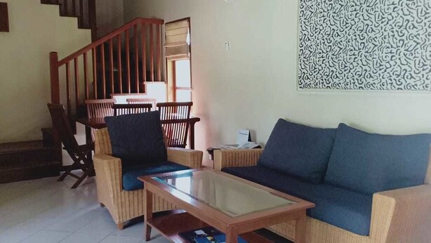 A living room with a sofa, chairs, a coffee table, and a staircase. - Tanjung Lesung Beach Hotel (Tanjungjaya)