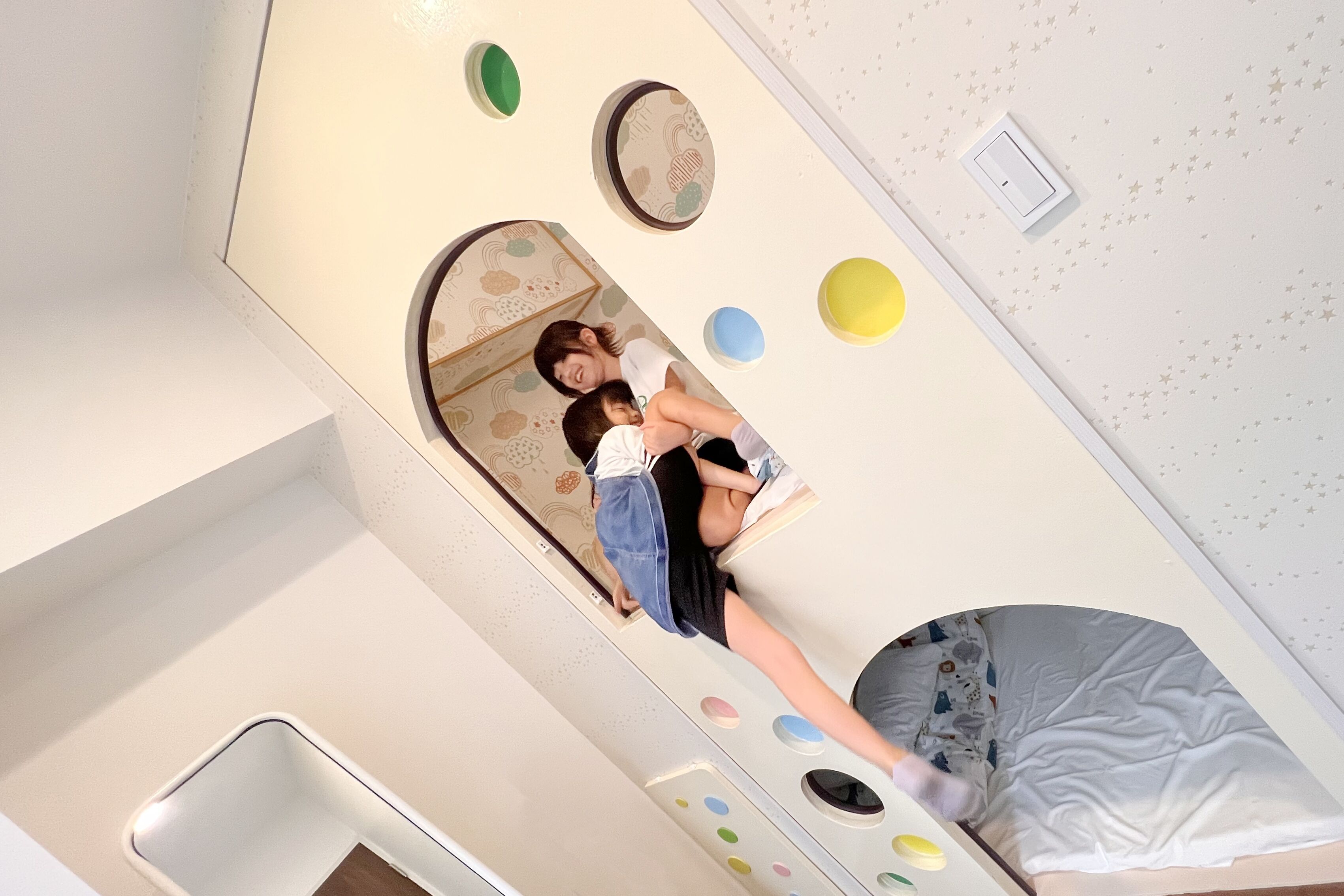 A room with a bed, a mirror, and a wall with circular cutouts.