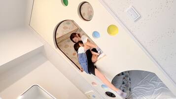 A room with a bed, a mirror, and a wall with circular cutouts.