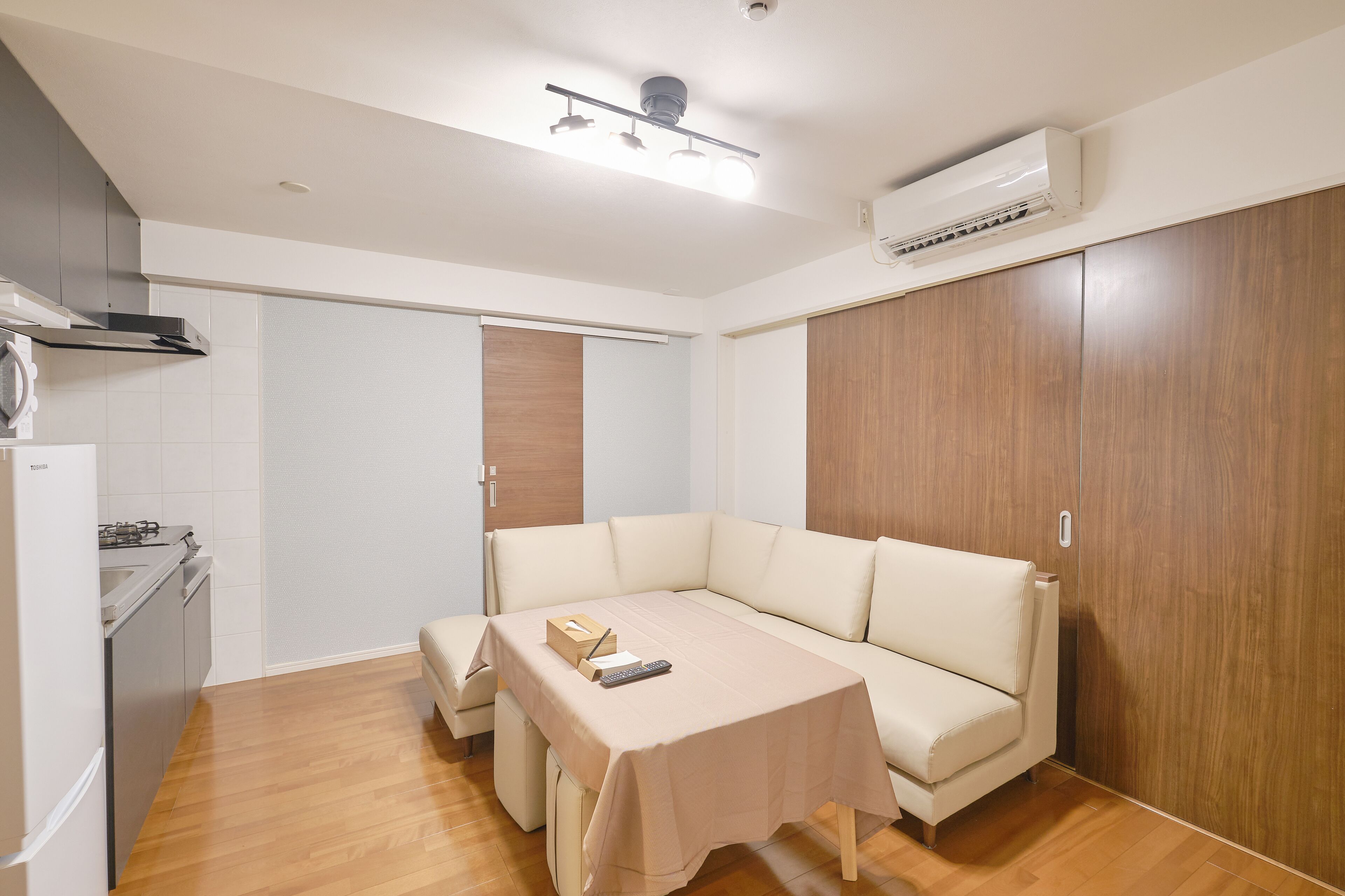 A compact living space with a kitchenette, a sofa, and a table.