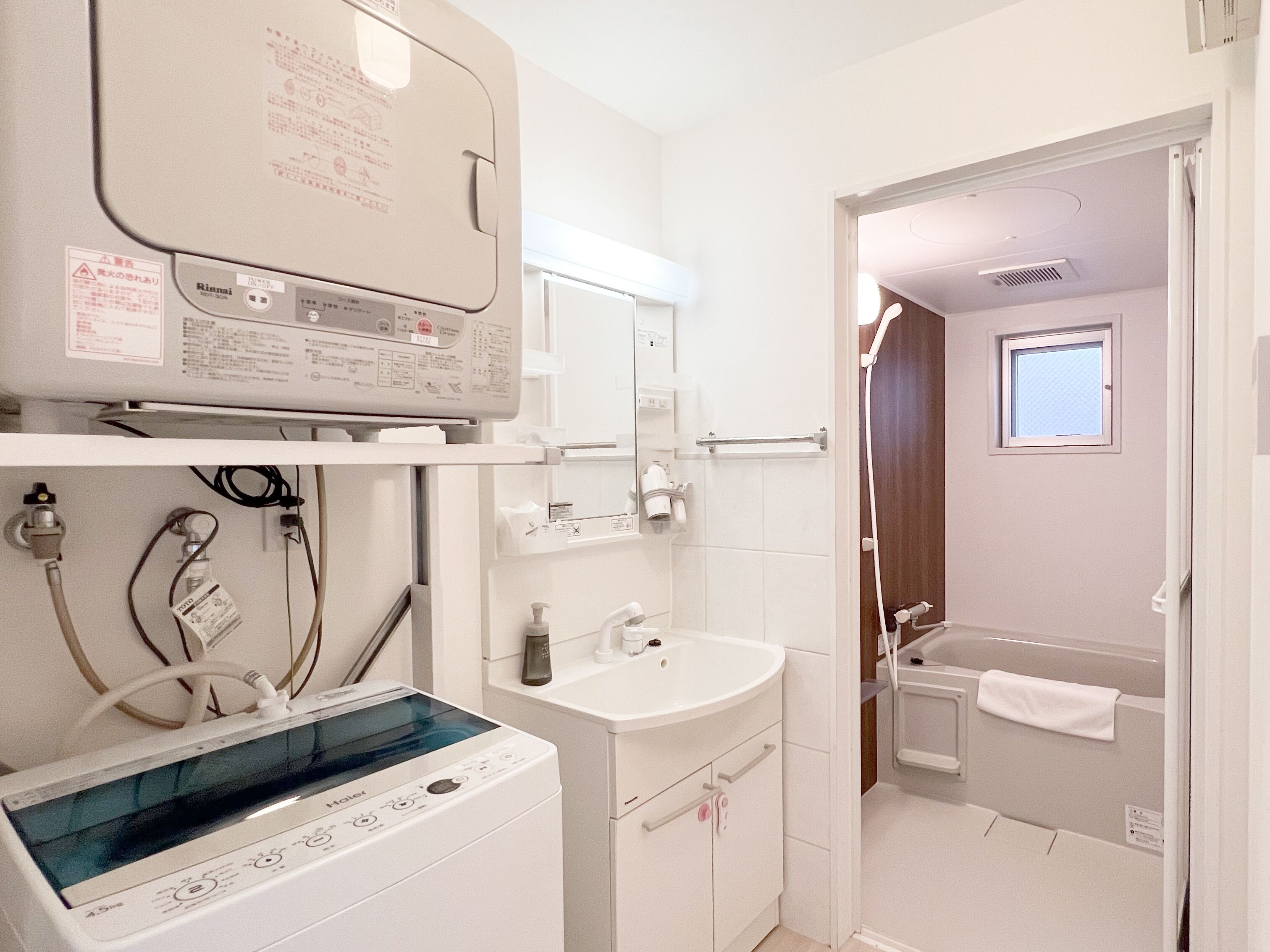 A compact bathroom with a built-in washer and dryer, a sink, and a shower area.