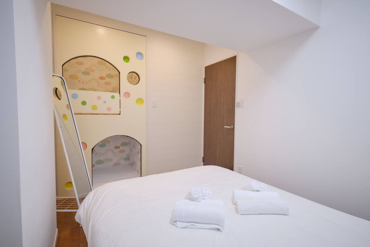 Una cama bien hecha con toallas, una puerta de madera y una pared con un diseño circular.