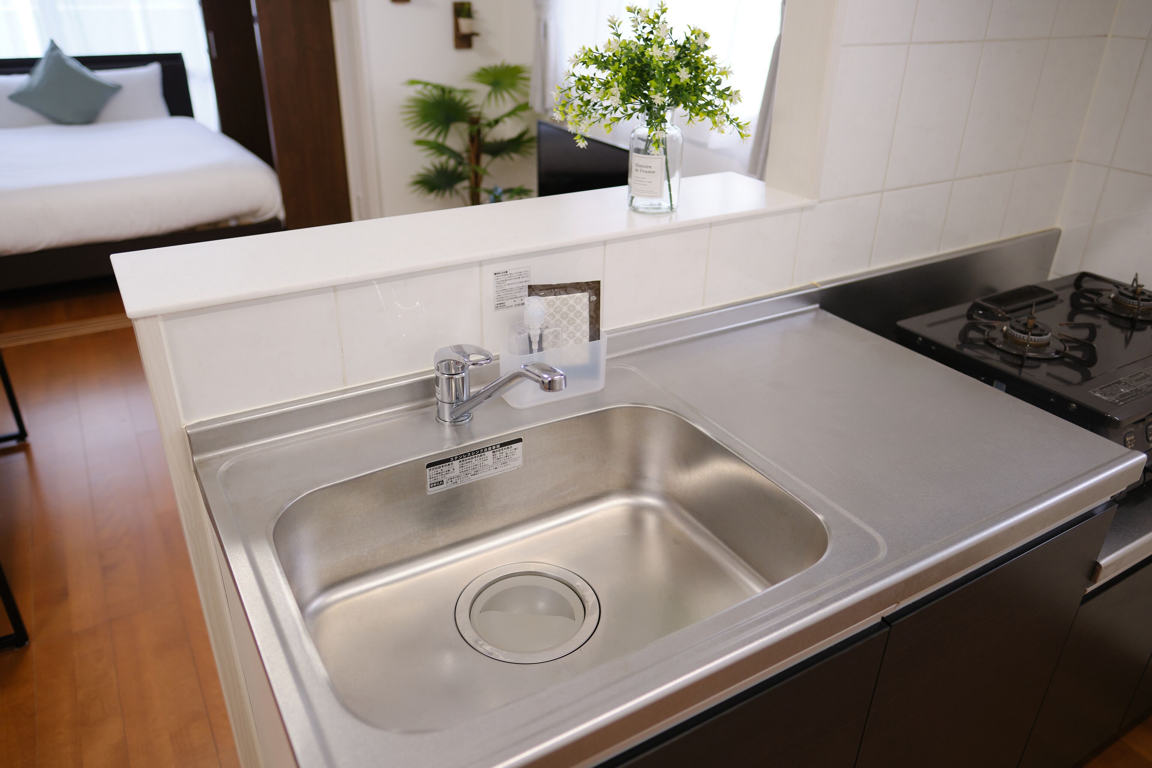 Una cocina moderna con un lavamanos de acero inoxidable, una estufa empotrada y una encimera blanca.