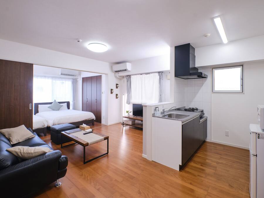 Un espacio habitable compacto con kitchenette, una cama, un sofá y una pequeña zona de comedor.