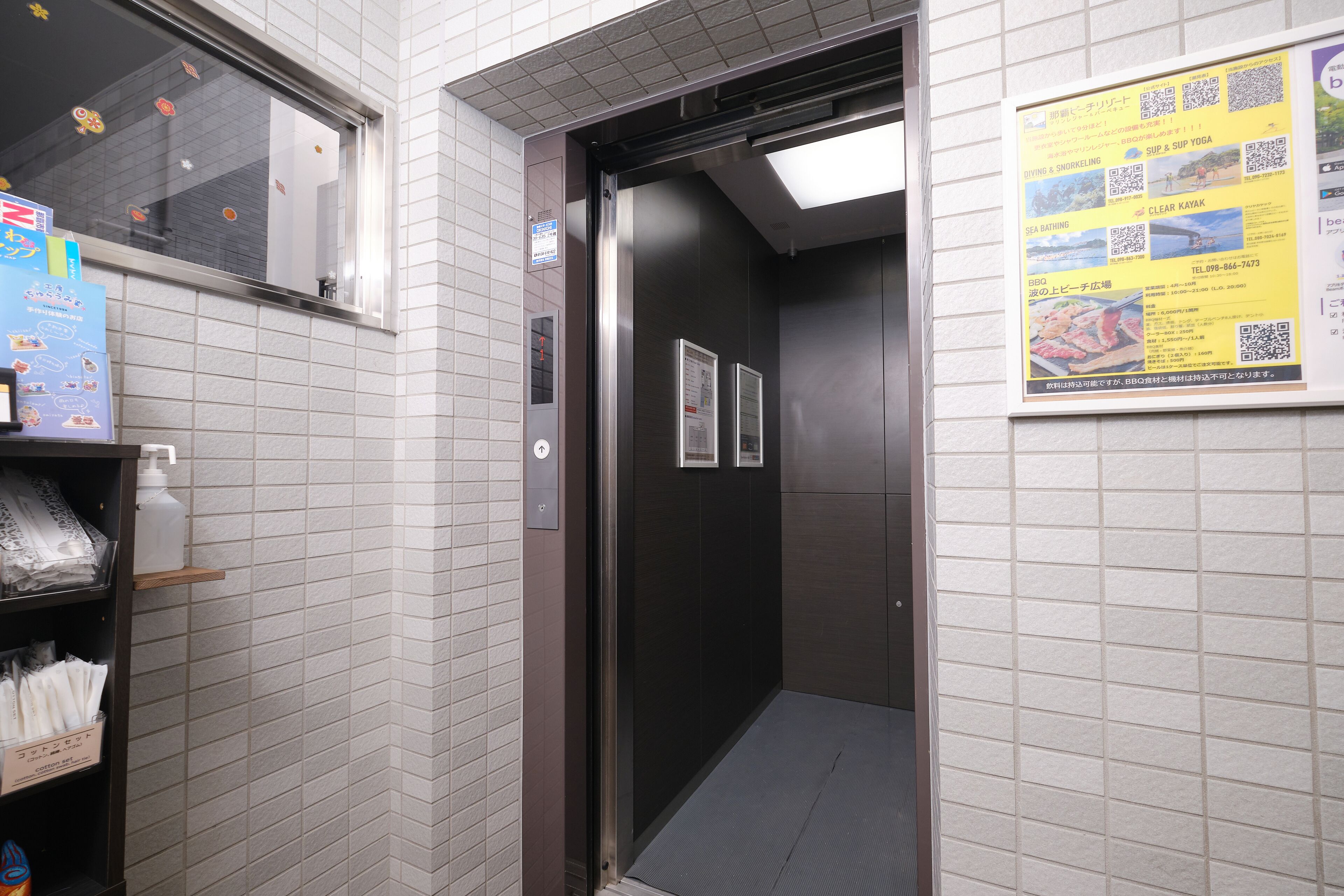 An elevator interior with a tiled wall, a door, and a poster advertising local attractions.