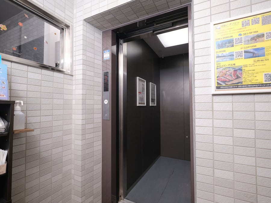 An elevator interior with a tiled wall, a door, and a poster advertising local attractions.