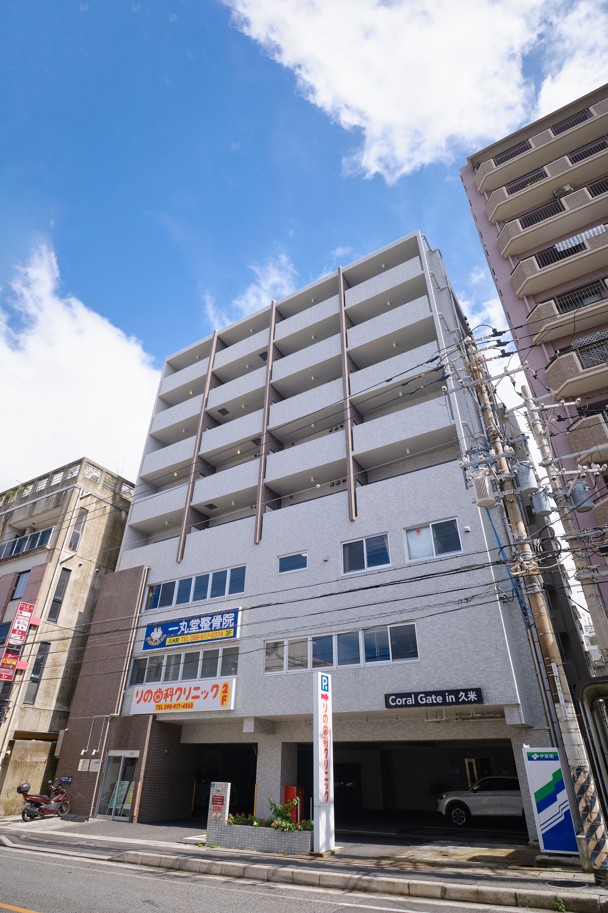 A multi-story building with a parking garage entrance, a sign for a dental clinic, and a sign for a hotel named "Coral Gate in Utsunomiya".
