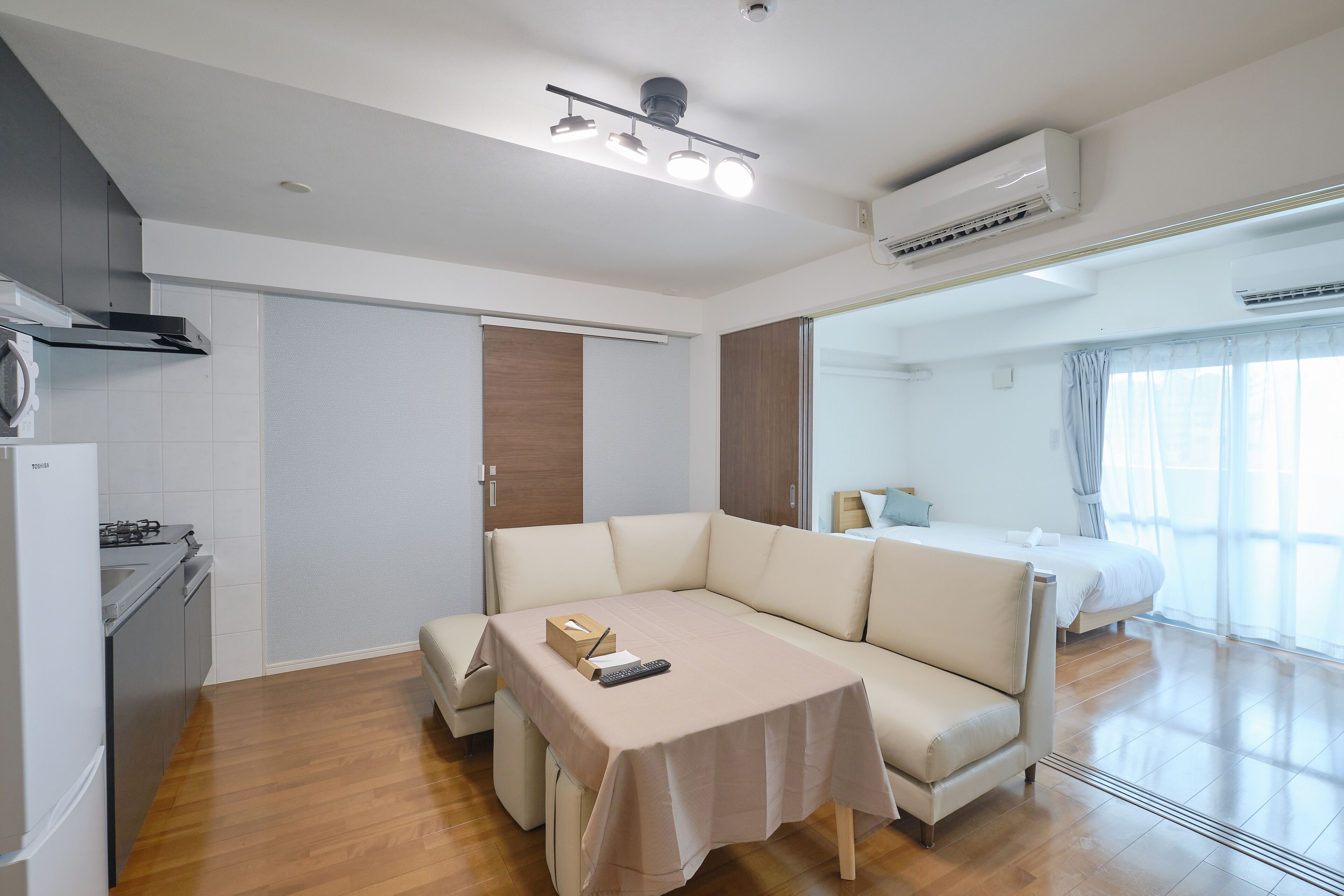 Una habitación moderna y bien iluminada con kitchenette, un sofá cama y una mesa de comedor.