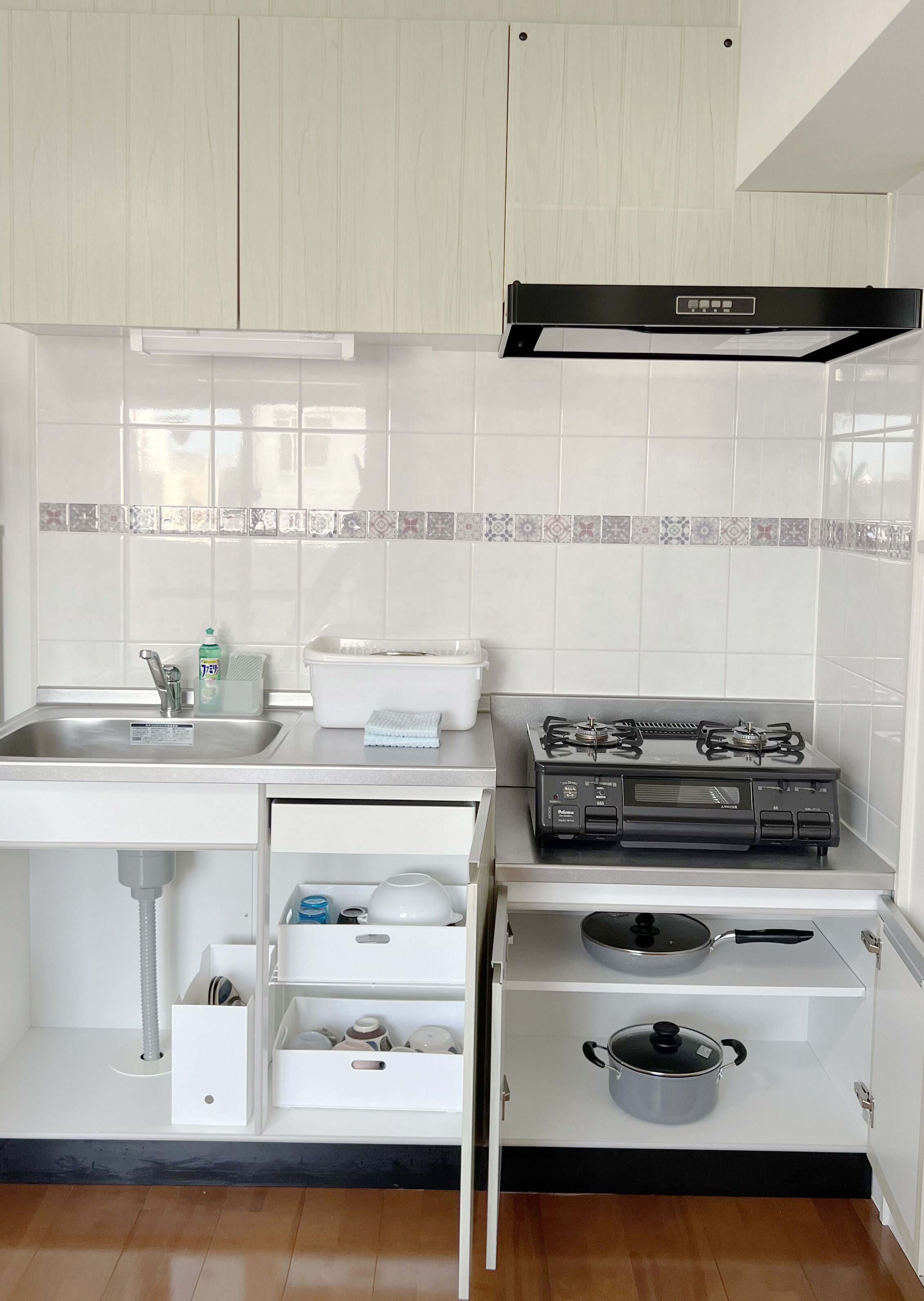 A compact kitchen with white cabinets, a stainless steel sink, a gas stove, and a built-in oven.