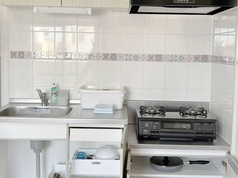 A compact kitchen with white cabinets, a stainless steel sink, a gas stove, and a built-in oven.