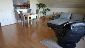 A modern living room with a sofa, a dining table with chairs, and a potted plant. - Zur schönen Aussicht (Hellenthal)