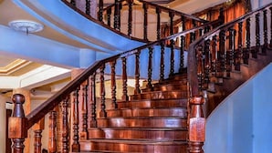 Eine imposante Holztreppe mit aufwendig gestalteten Geländern und einem gewölbten Verlauf, die zu einer oberen Etage führt.