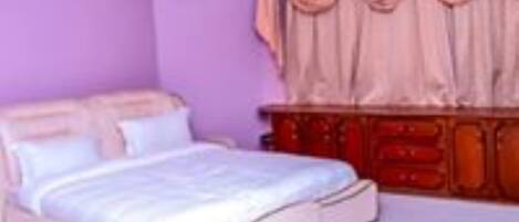 A bedroom with a bed, a dresser, and a chandelier.