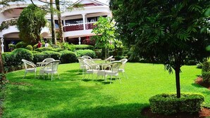 Ein gepflegter Garten mit ordentlich gestutztem Rasen, weißer Gartenmöbel und einem Gebäude im Hintergrund.
