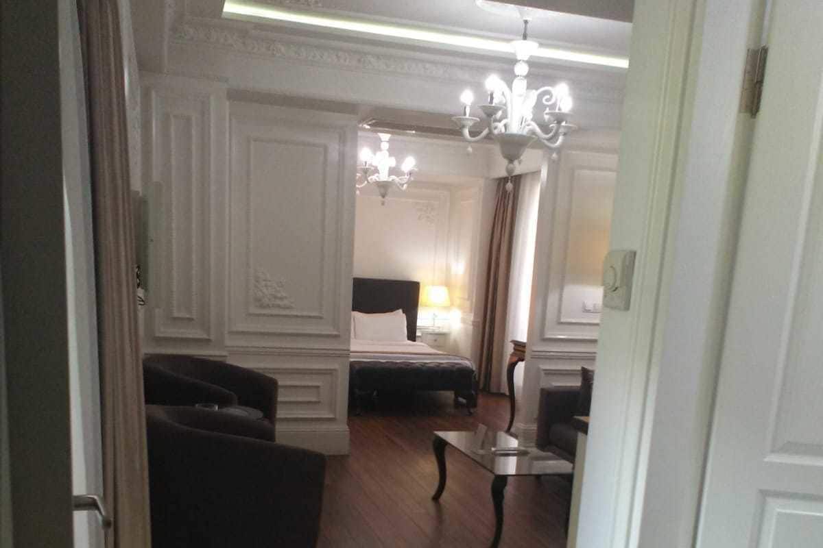 A hotel lobby with a checkered floor, a sofa, a bed, and a chandelier.
