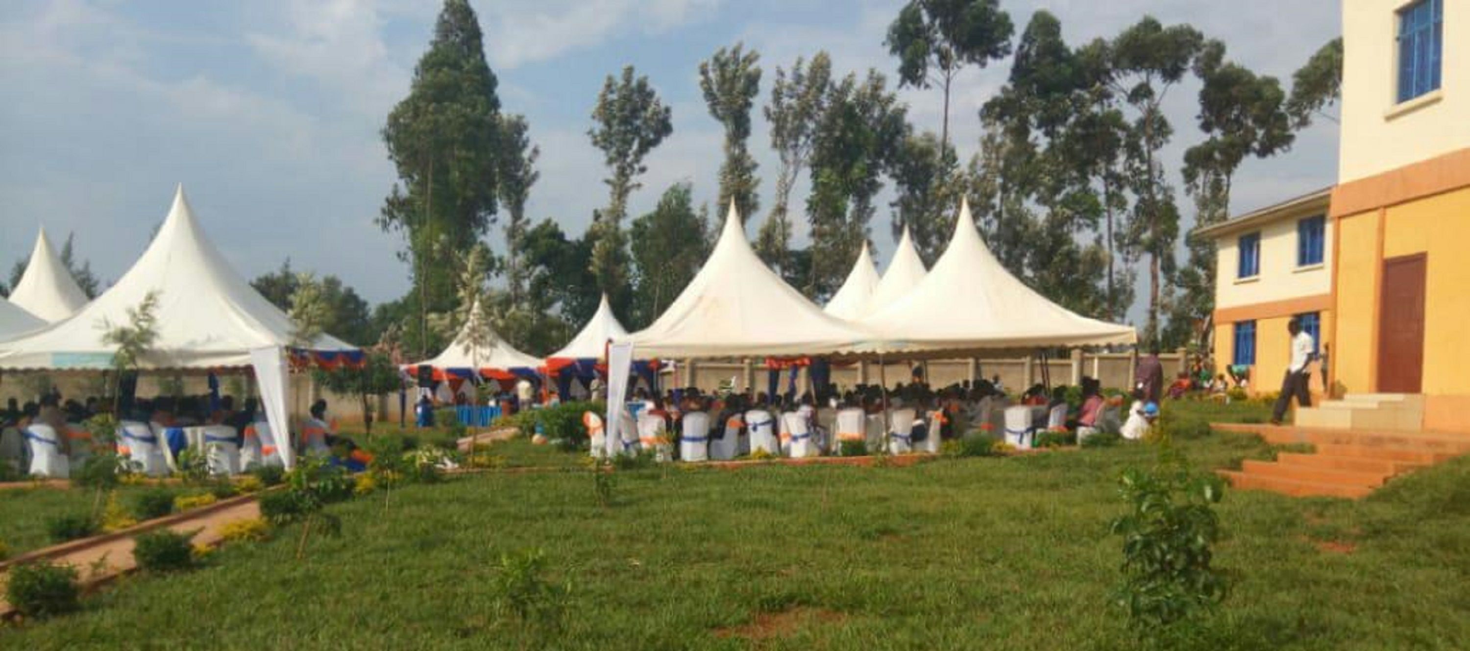 A grassy outdoor area with multiple white tents and a building in the background.