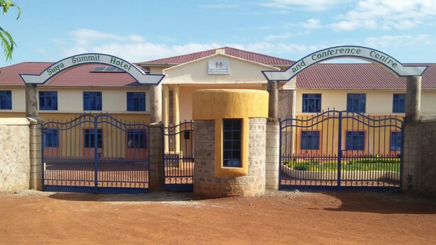 A hotel with a gated entrance, a yellow building, and a sign indicating a conference center. - Siaya Summit Hotel (Siaya)