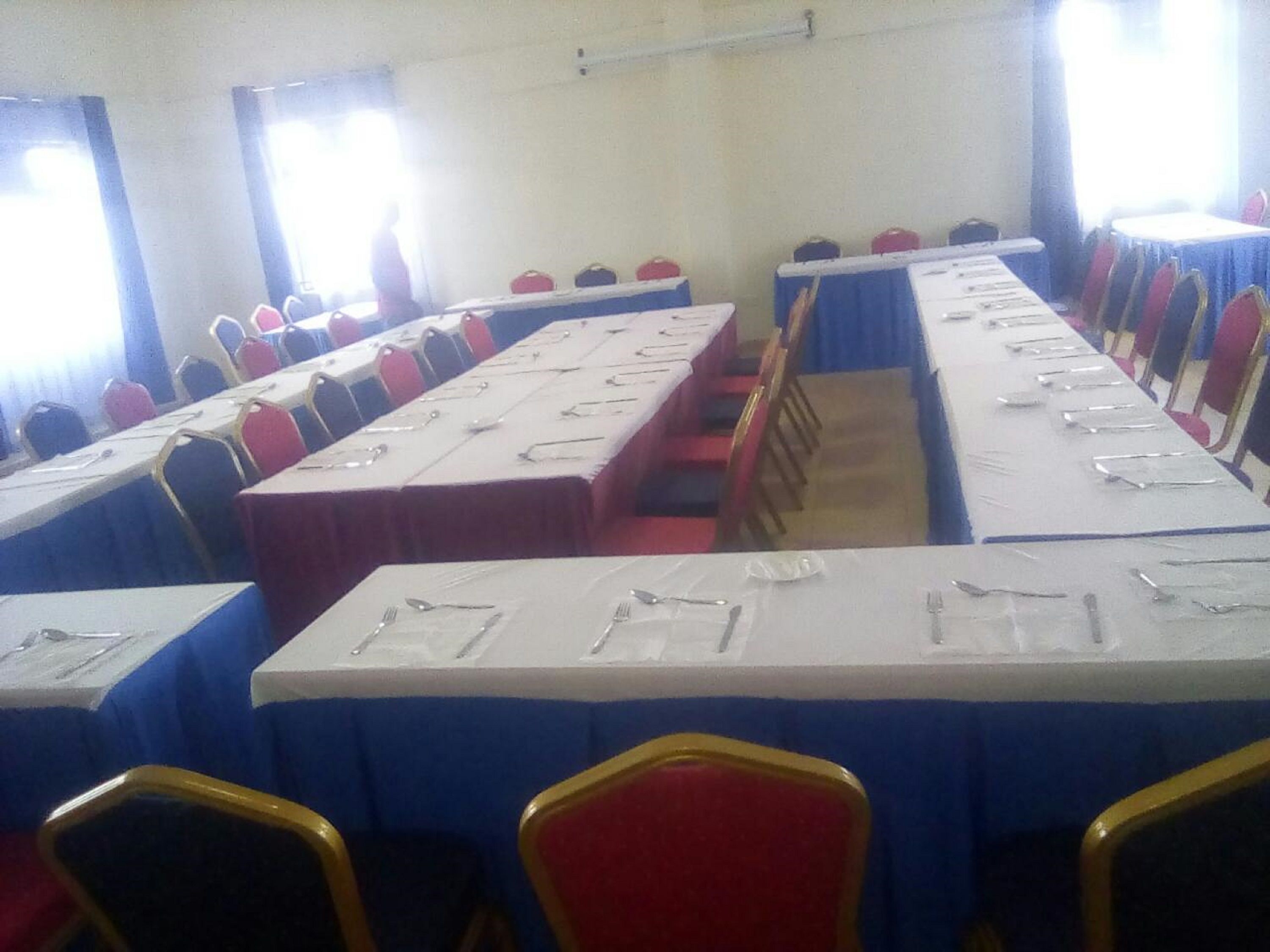 Une salle de conférence avec de longues tables disposées pour les réunions, équipée de plaques nominatives et de fournitures de bureau.