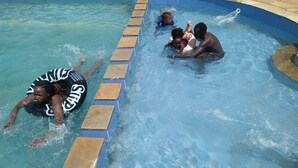 A swimming pool with clear blue water, stone steps, and a person floating on an inflatable ring. - Siaya Summit Hotel (Siaya)