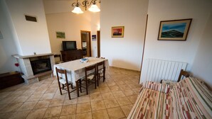 A dining area with a table and chairs, a fireplace, and a television. - La Fattoria dei Sibillini (Montemonaco)