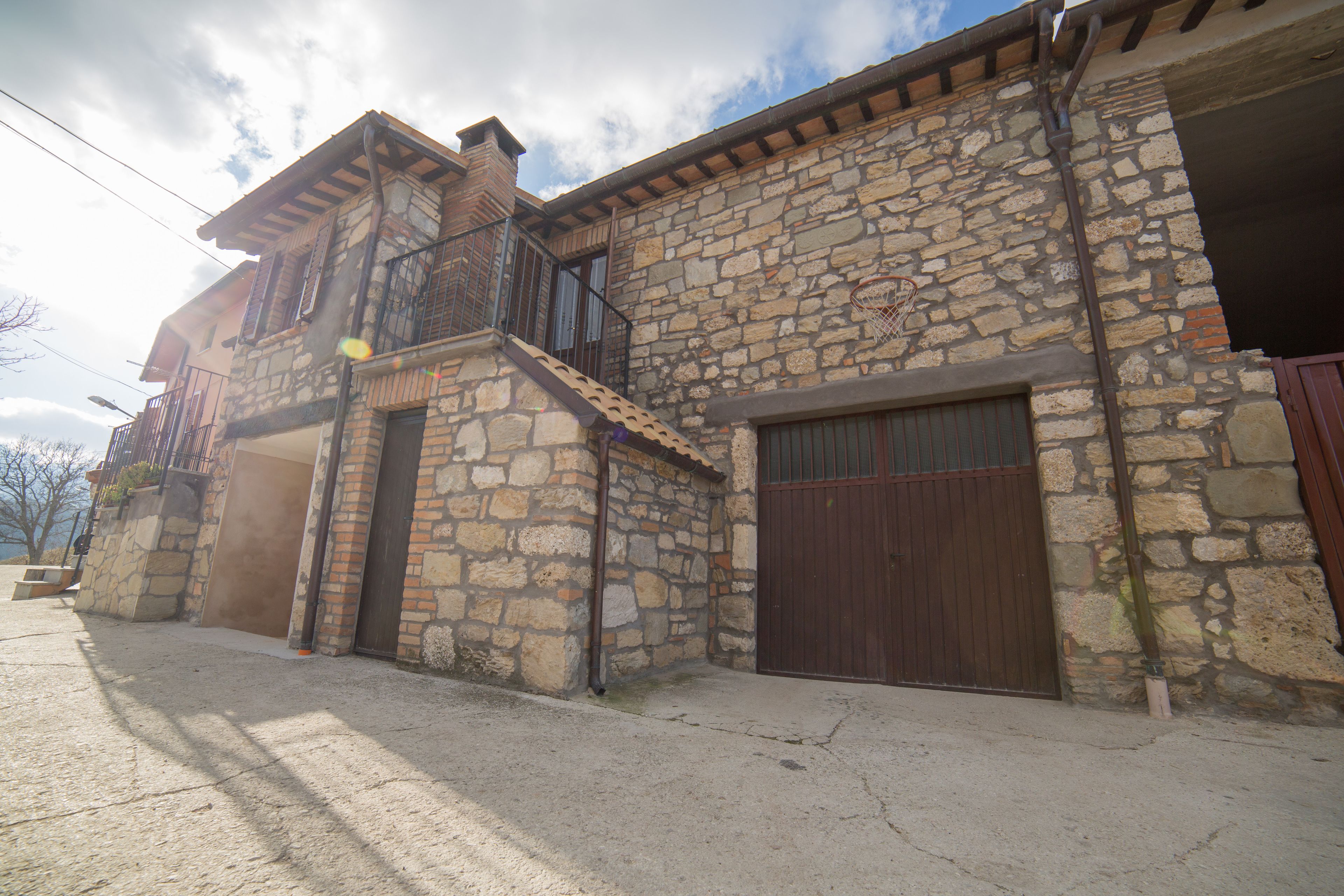 A stone building with a balcony and a garage door.