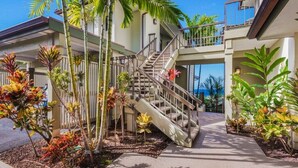 A multi-story building with a central staircase, surrounded by tropical plants. - ONE of Our BEST! Fresh Pricing, UPSCALE Renovations; (22V-1) where you get HUGE OCEAN Views (Lahaina)