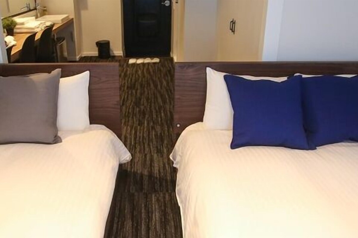 Une chambre d’hôtel avec deux lits, chacun étant équipé d’un oreiller et d’une tête de lit.