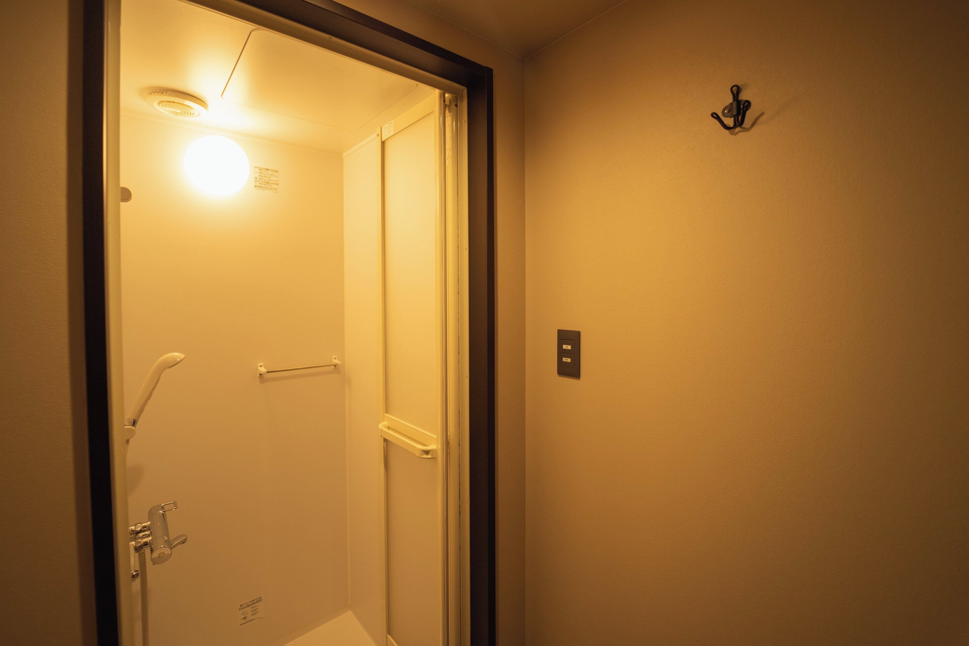 A bathroom with a shower, a towel rack, and a light fixture.