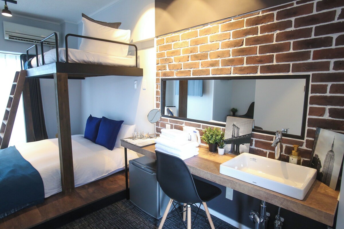 Une chambre avec un lit superposé, un bureau, un lavabo et un miroir.