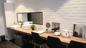 Ein modernes Badezimmer mit einem Holzkonsolentisch, einem großen Spiegel, einem Waschbecken, einer kleinen Pflanze und einem gerahmten Bild an der Wand.