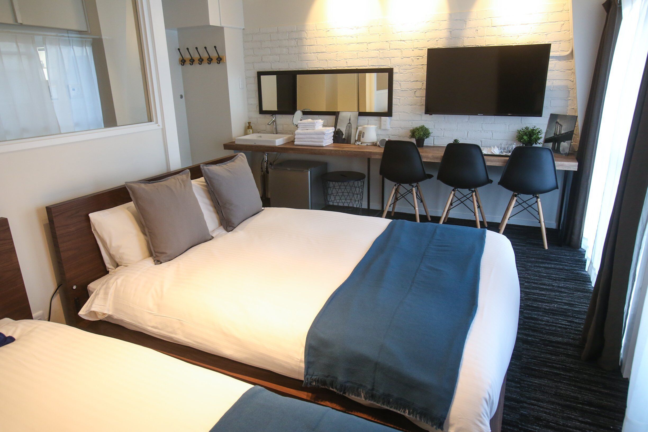 Una habitación de hotel con cama, escritorio con espejo, televisor y una planta pequeña.