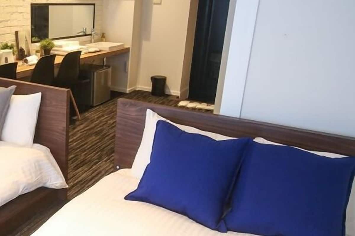 Een hotelkamer met twee bedden, een bureau en een badkamer.
