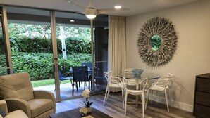 Ein modernes Wohnzimmer mit Sofa, Couchtisch und Essbereich mit Stühlen und einem Glastisch.