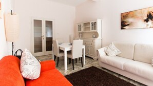 A living room with a white sofa, a red sofa, a dining table with chairs, a white cabinet, and a chandelier. - Acquadimare (Viareggio)