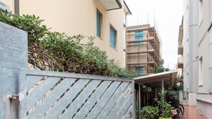 A narrow alleyway with a metal gate, a building with a balcony, and a parked bicycle. - Acquadimare (Viareggio)